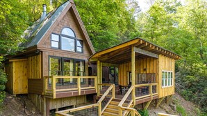 A wooden cabin with a balcony and a covered porch, surrounded by trees. - The Riverside Cabin! (Blue Ridge)