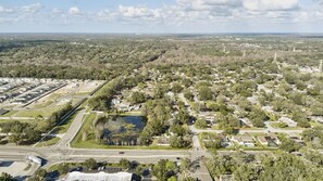 An aerial view of a residential area with houses, roads, and a large body of water. - Stunning Home w/ Heated Saltwater Pool & Pond View + 12 Guests + Great Location (Temple Terrace)