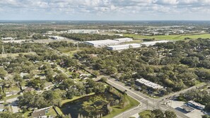 An aerial view of a residential area with a large industrial facility in the background. - Stunning Home w/ Heated Saltwater Pool & Pond View + 12 Guests + Great Location (Temple Terrace)