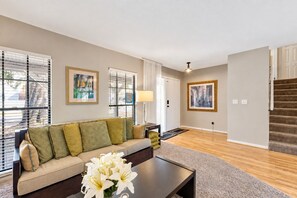 A living room with a sofa, coffee table, and artwork on the walls. - Stunning Home w/ Heated Saltwater Pool & Pond View + 12 Guests + Great Location (Temple Terrace)