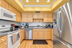 A modern kitchen with stainless steel appliances, wooden cabinets, and a granite countertop.