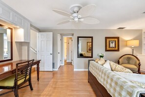 A hotel room with a bed, a desk, a chair, a ceiling fan, and a mirror. - Stunning Home w/ Heated Saltwater Pool & Pond View + 12 Guests + Great Location (Temple Terrace)