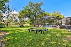 An outdoor patio area with a pool, covered seating, and a view of a lake. - Stunning Home w/ Heated Saltwater Pool & Pond View + 12 Guests + Great Location (Temple Terrace)