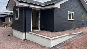 Una casa moderna con fachada oscura, molduras blancas y techo inclinado.