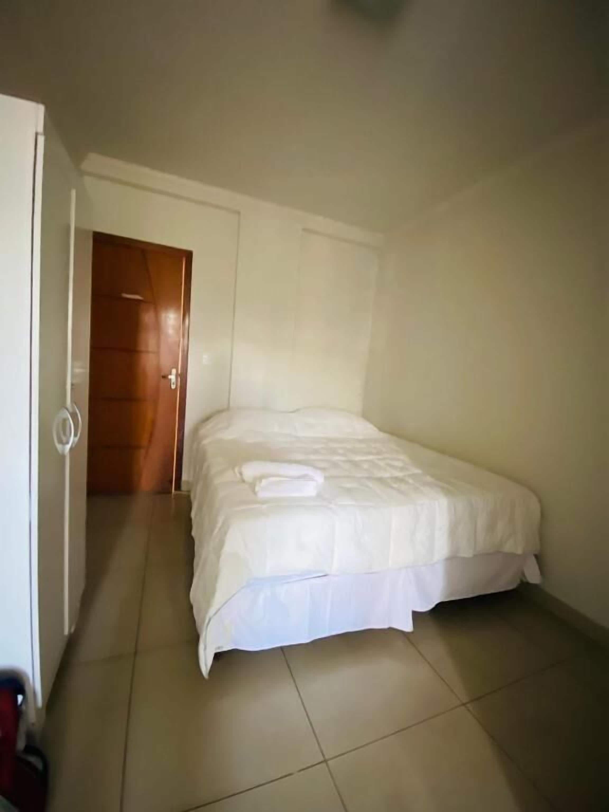 Un dormitorio con cama, puerta y suelo de baldosas.