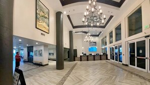 A spacious lobby with a herringbone floor pattern, a large chandelier, and a reception desk. - Gorgeous Sunset Condo at One of the Most Beautiful Pool Resorts on the Beach!  (Panama City Beach)