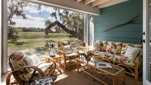 A room with a large sliding glass door leading to a grassy outdoor area, wicker furniture, and a teal-colored wall.