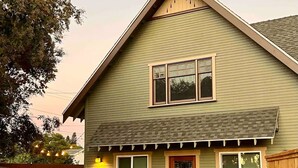 A two-story house with a gabled roof, a front porch, and a small front yard. - Villa Verde - 5 miles to Disney! (Fullerton)