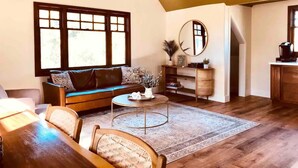 A cozy living room with a sofa, coffee table, and a dining area. - Villa Verde - 5 miles to Disney! (Fullerton)