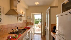 A kitchen with a stove, sink, and washing machine, leading to an outdoor patio.