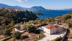 A coastal property with two buildings labeled 'Kristi' and 'Tina'. The property features a paved driveway, a swimming pool, and is surrounded by dense vegetation and a mountainous backdrop. - Kristi - Three Bedroom Villa, Sleeps 6 (Spartochori)