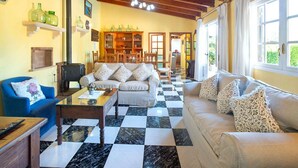 A spacious living room with a checkered floor, a sofa set, a coffee table, and a blue armchair.