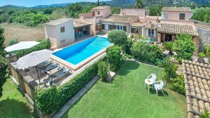 A villa with a swimming pool, outdoor seating, and a lush garden.