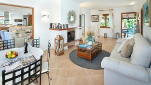 A spacious living area with a fireplace, a dining table with chairs, and a sofa. - C'an Pontarro - Five Bedroom Villa, Sleeps 10 (Mallorca)