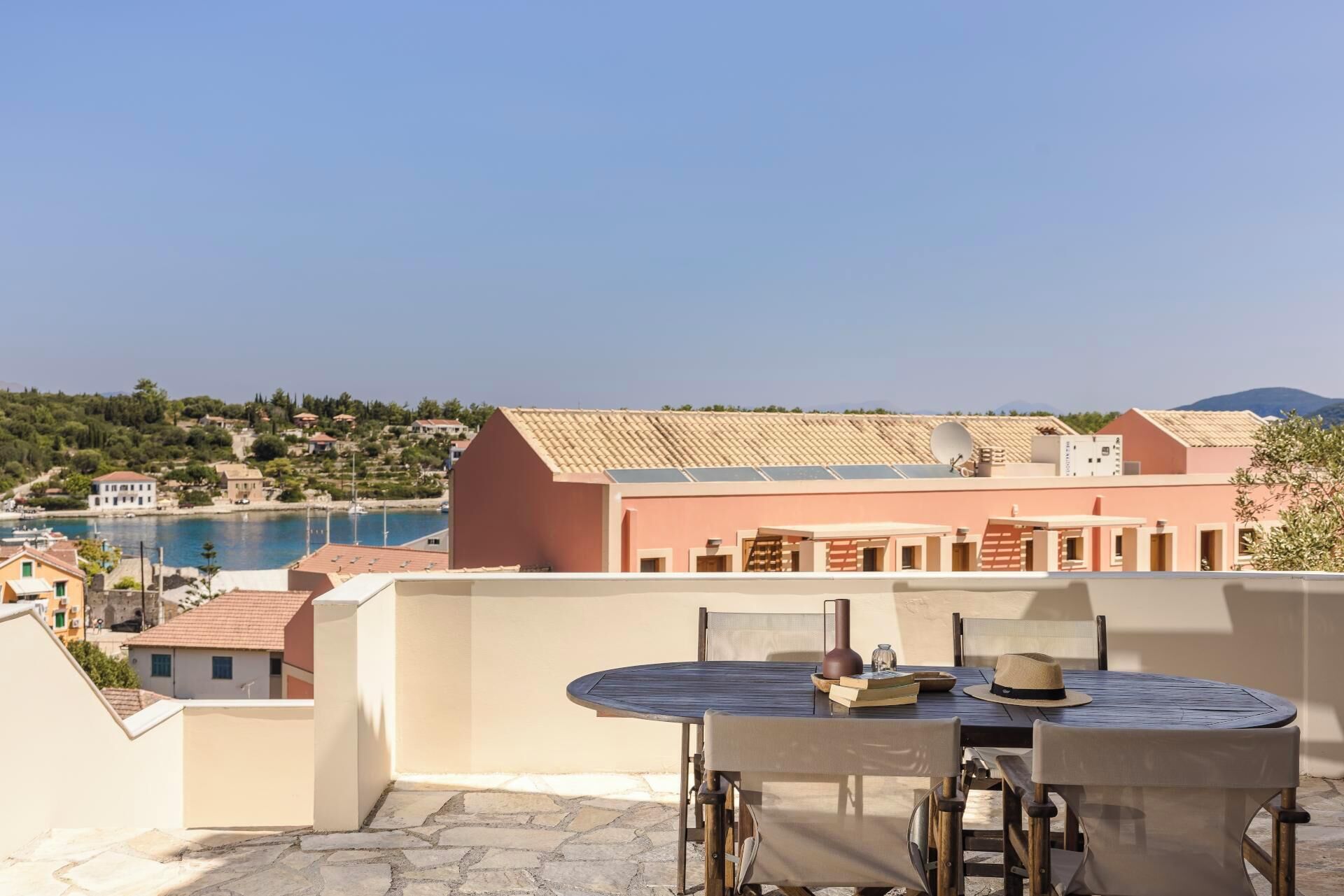 Une terrasse avec une table et des chaises donnant sur une piscine et une colline.