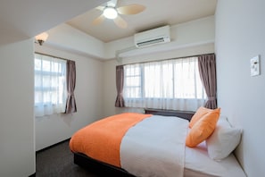 A hotel room with a bed, an air conditioner, a ceiling fan, and two windows with curtains. - Deluxe Room 1 double bed  1 queen bed with kitc / Miyazaki Miyazaki (Miyazaki)