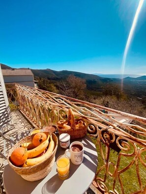 A breakfast setup on a balcony with a scenic mountain view. - 6 Bedroom Private vacation home in Pietracorbara (Pietracorbara)