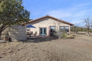 A single-story building with a beige exterior, a blue door, and a small patio area with a table and chairs.