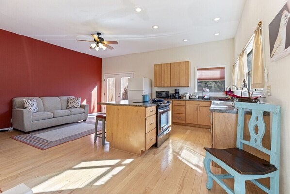 A compact living space with a kitchenette, a sofa, a dining table, and a ceiling fan.