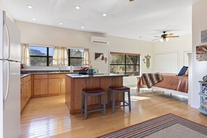 A spacious kitchen with wooden cabinets, a central island, and two bar stools.