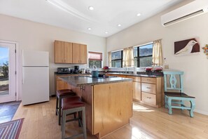 A spacious kitchen with wooden cabinets, a central island, and a large window.