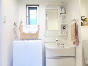 Ein kleines Badezimmer mit Waschmaschine, Spüle und Spiegel.