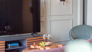A living room with a flat-screen TV, a wooden coffee table with a plate of grapes and two glasses of wine, and a bookshelf with books. - Riverside Oasis by LovelyStay (Vila Nova de Gaia)