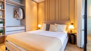 A hotel room with a bed, bedside lamps, a wardrobe, and a shelf with plants. - Riverside Oasis by LovelyStay (Vila Nova de Gaia)
