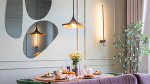 A dining area with a round table set for breakfast, a vase with yellow flowers, and a green plant.