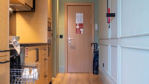 A narrow hallway with wooden cabinets, a door with a notice, and a wall-mounted telephone.