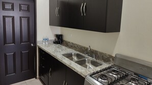 A kitchen with dark cabinets, a granite countertop, a double sink, and a gas stove. - Cómodo Departamento Y Para Cuatro Personas, Cerca del Aeropuerto de Loreto (Loreto)