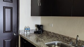 A kitchen with dark cabinets, a granite countertop, a stainless steel sink, and a coffee maker. - Cómodo Departamento Y Para Cuatro Personas, Cerca del Aeropuerto de Loreto (Loreto)