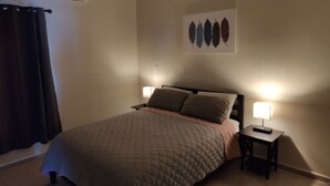 A bedroom with a bed, two bedside lamps, a ceiling fan, an air conditioning unit, a dark curtain, and a wall-mounted artwork. - Cómodo Departamento Y Para Cuatro Personas, Cerca del Aeropuerto de Loreto (Loreto)