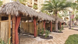 Un resort con cabañas de techo de paja, palmeras y sillas de descanso.