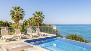 A poolside area with lounge chairs and a view of the ocean.