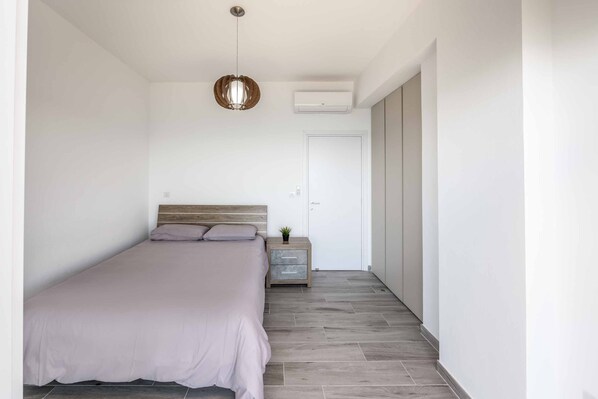 A bedroom with a bed, bedside table, and a hanging light fixture.