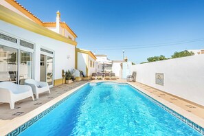 A swimming pool with clear blue water, surrounded by white walls and a yellow roof.