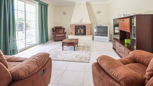 Ein Wohnzimmer mit Kamin, Fernseher und Holzschrank.