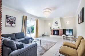 A living room with a sofa, armchairs, a coffee table, a fireplace, and a television.