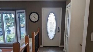A hallway with a tiled floor, a wooden railing, and a door with a frosted glass window.