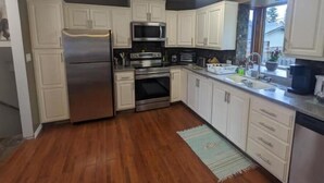 A kitchen with white cabinets, stainless steel appliances, and a wooden floor.