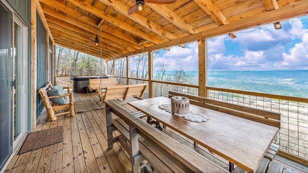 Una terraza de madera con una mesa y bancos, con vistas a un paisaje pintoresco.