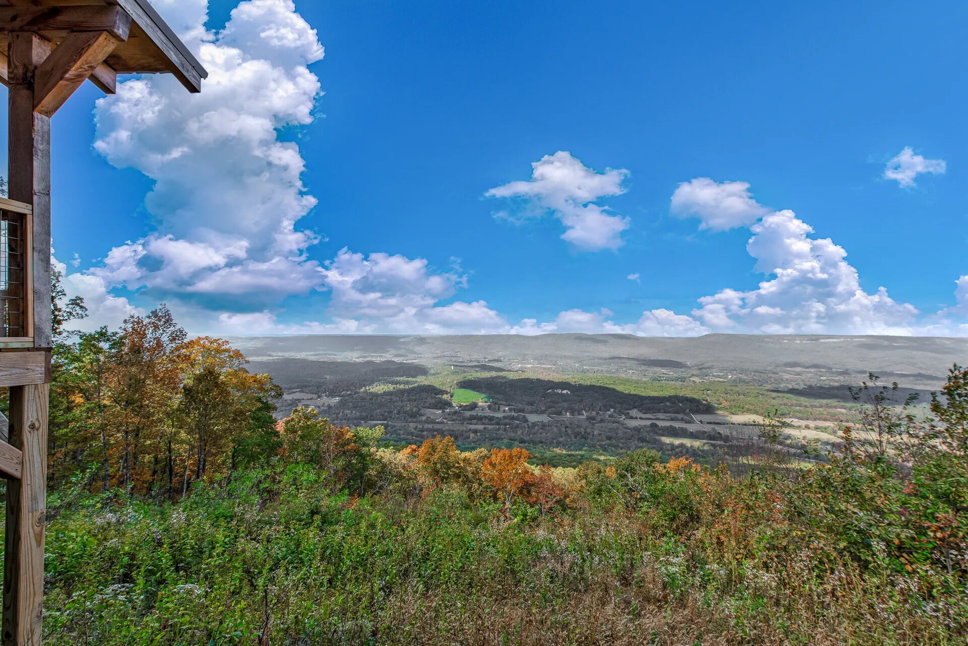 Une cabane en bois offrant une vue sur un paysage vallonné et un ciel bleu dégagé.