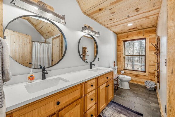 A modern bathroom with wooden cabinetry, a white sink, and two large mirrors.