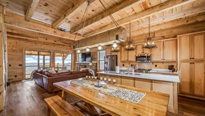 Una cocina amplia con vigas de madera, una isla central y un comedor con banco.