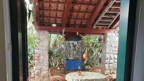 Un patio con una mesa redonda y sillas, un comedero para pájaros y un pequeño recipiente azul.