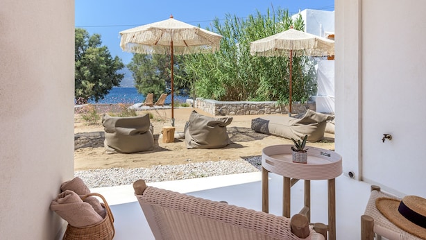 Un espace extérieur moderne, aménagé avec des meubles en osier et des parasols, offrant une vue panoramique sur la côte.