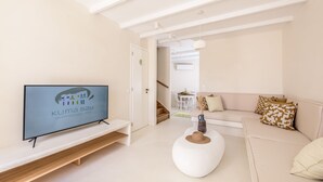 Una sala moderna con un televisor de pantalla plana, un sofá blanco y una mesa de centro redonda.