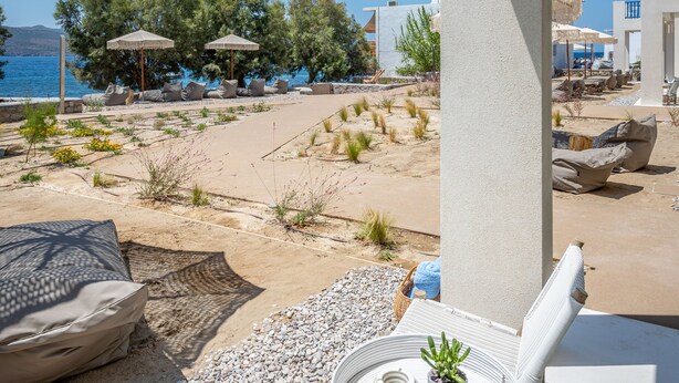 Un balcon avec vue sur la mer, des sièges d’extérieur et une table agrémentée d’une plante.