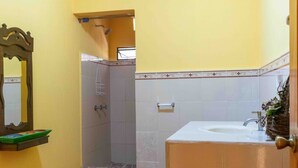 Un baño con ducha, lavamanos y espejo.